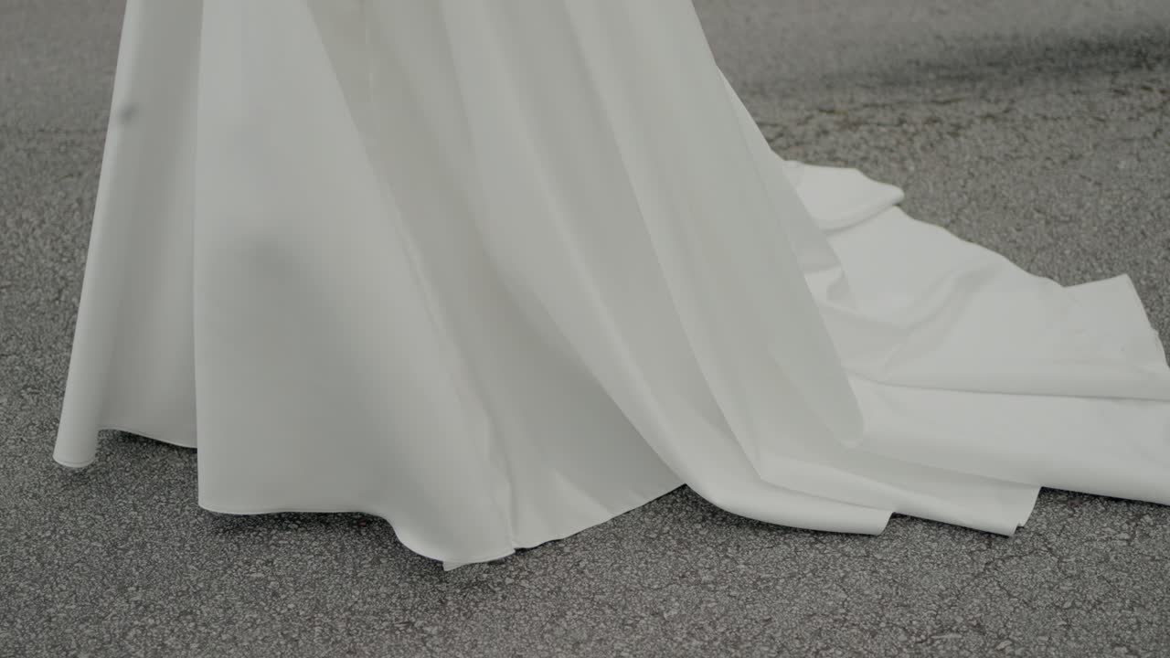 bride in white wedding gown holding bouquet on a road, highlighting dress details