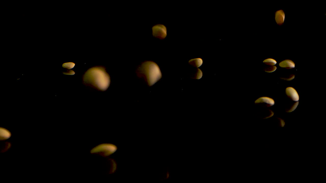 Lenticchie verdi che cadono su una superficie nera, al rallentatore