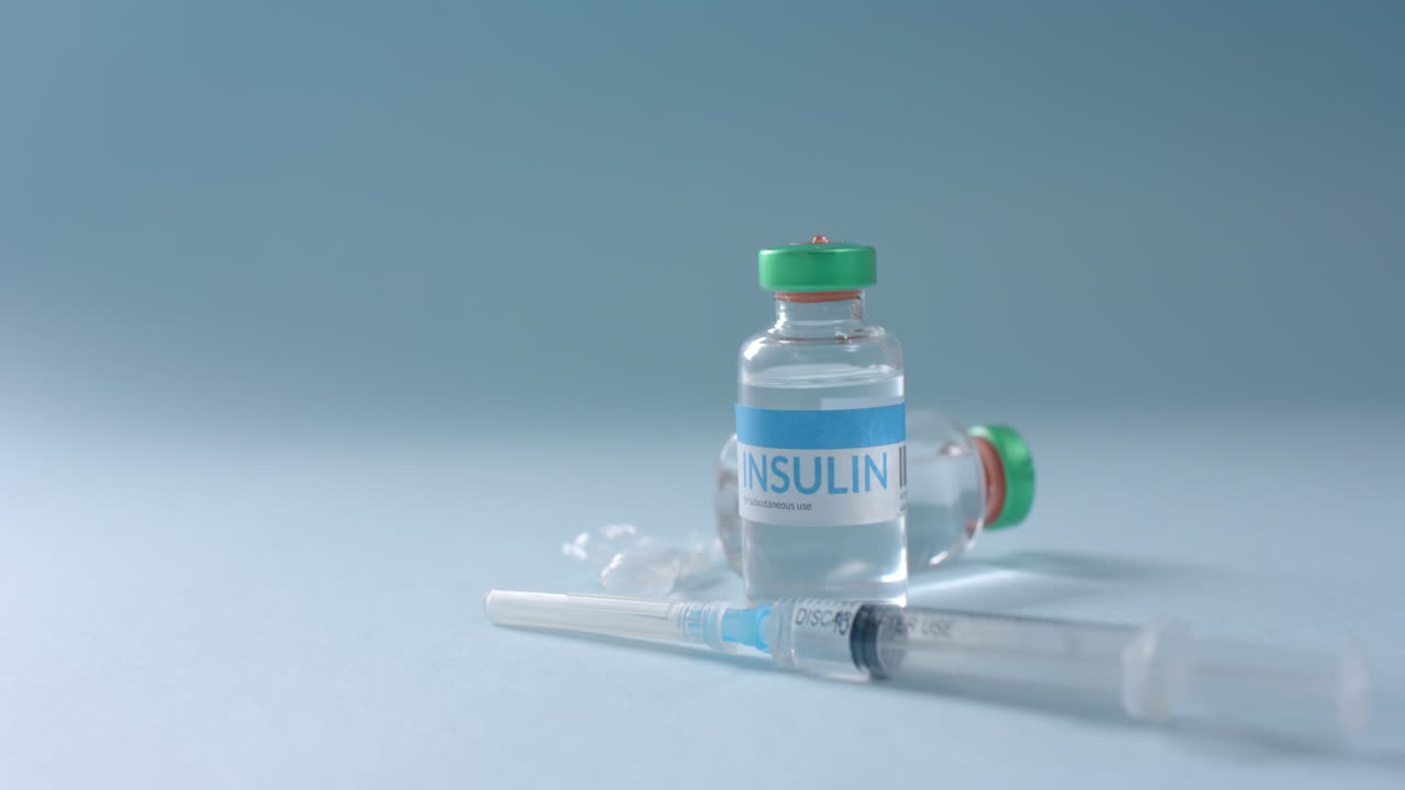 Close up of insulin vials and syringe on blue background with copy space, slow motion