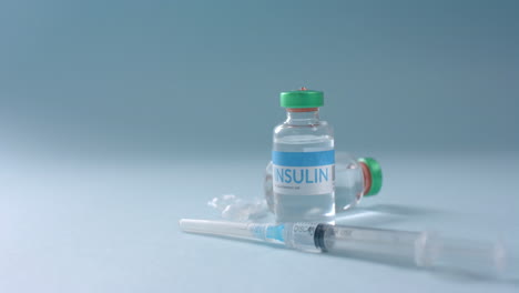 close up of insulin vials and syringe on blue background with copy space, slow motion