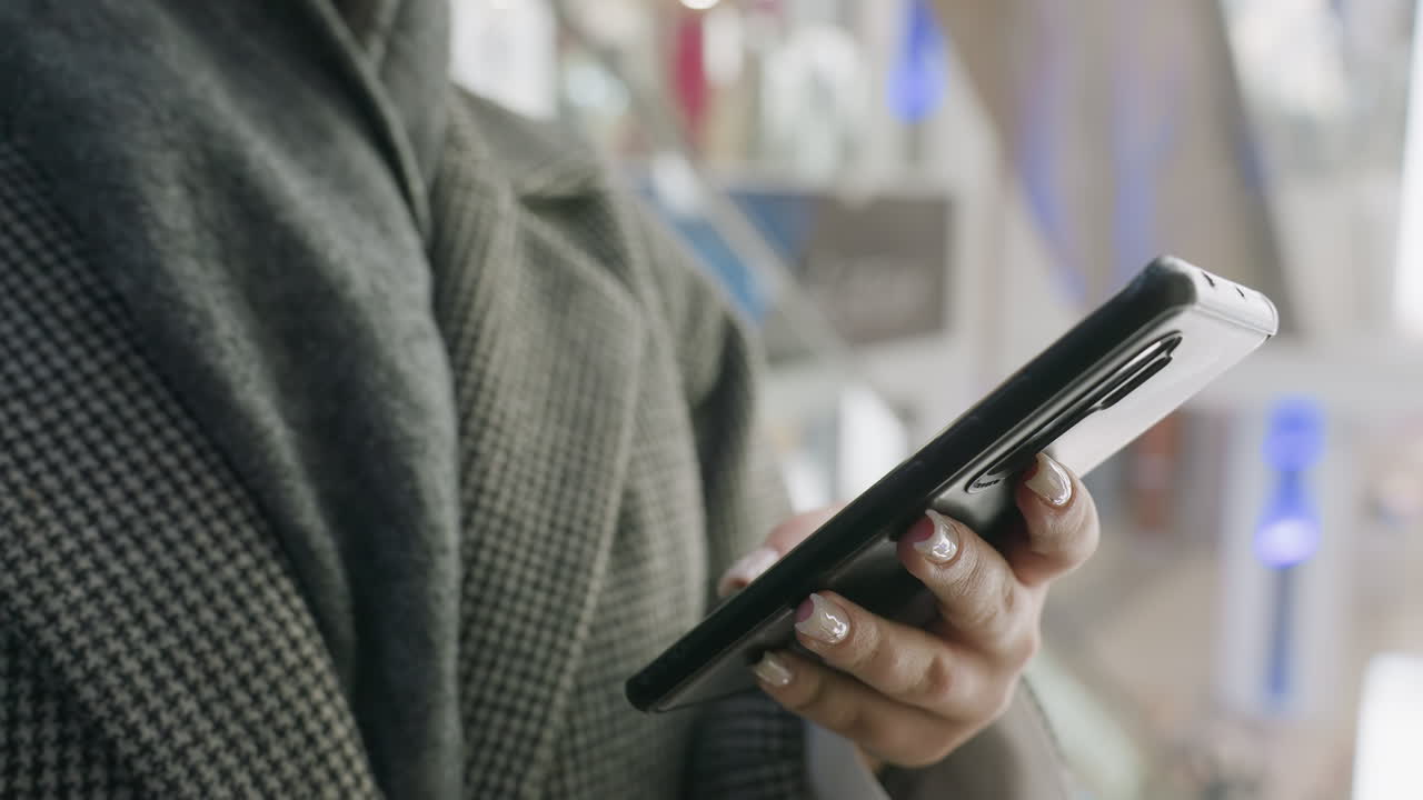 close up of stylish woman holding smartphone while standing inside ascending elevator with soft background lights and reflections adding modern indoor mall atmosphere