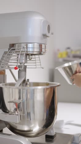 woman pouring ingredients into a mixer