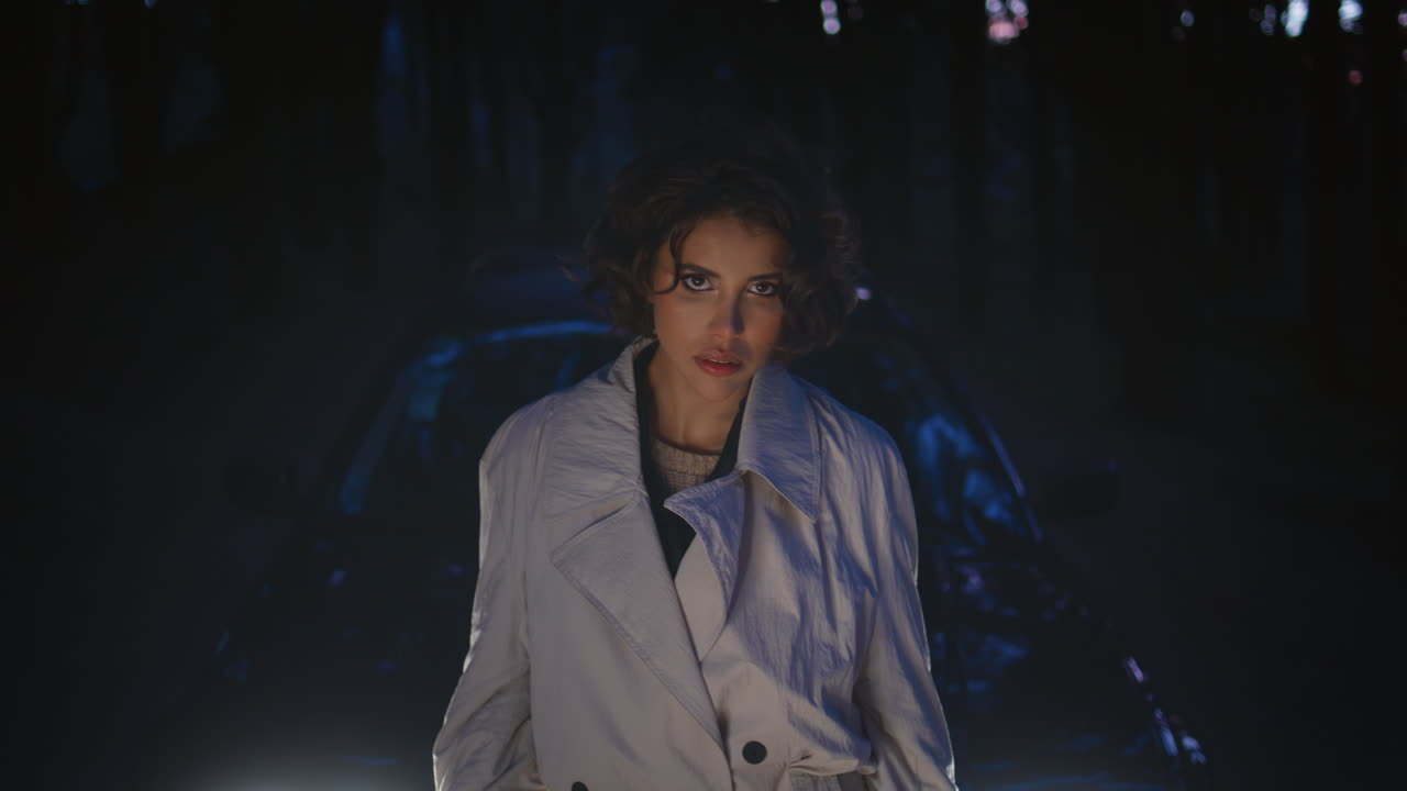 Confident driver posing car headlight in night forest closeup. Beautiful woman