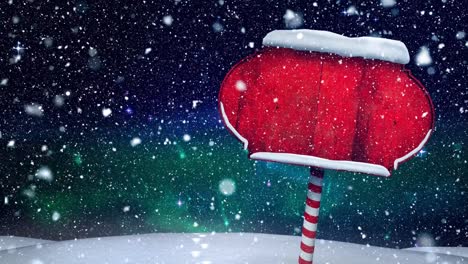 nieve cayendo sobre un poste de señales de madera roja en el paisaje de invierno contra el cielo nocturno