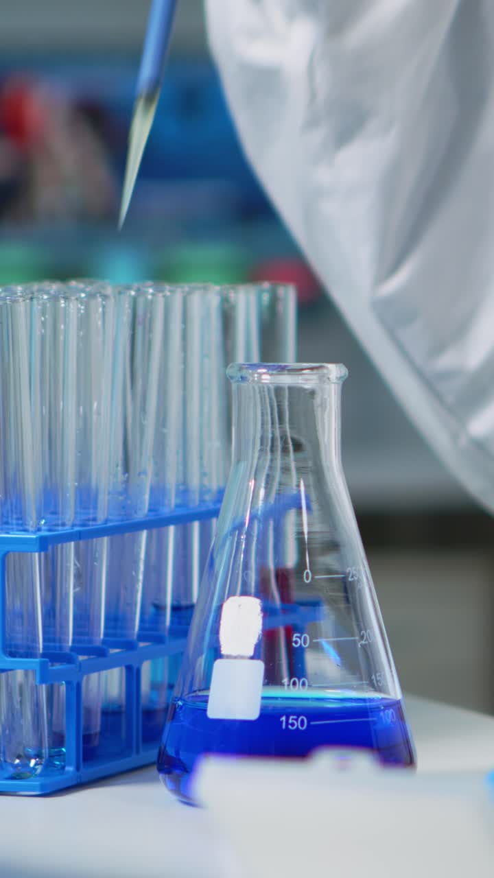 Vertical video: Close up of researcher testing liquid sample using micropipette