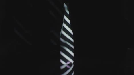 bars of light projected on a dark wine bottle