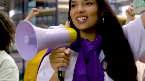 Mujer-Joven-Con-Megáfono-Y-Mujer-Con-Pancarta-En-Una-Protesta