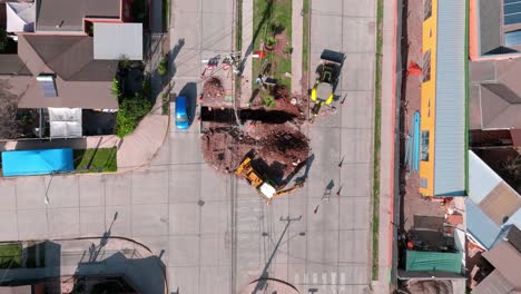 Overhead-dolly-in-view-of-heavy-machinery-performing-repair-work-on-the-public-road-in-broad-daylight