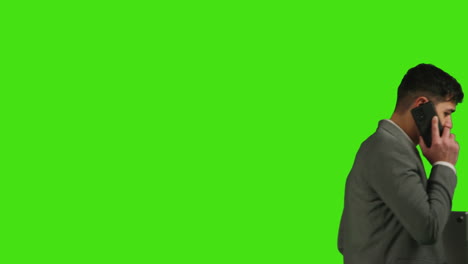 close up of businessman with laptop talking on mobile phone walking across frame against green screen background 1