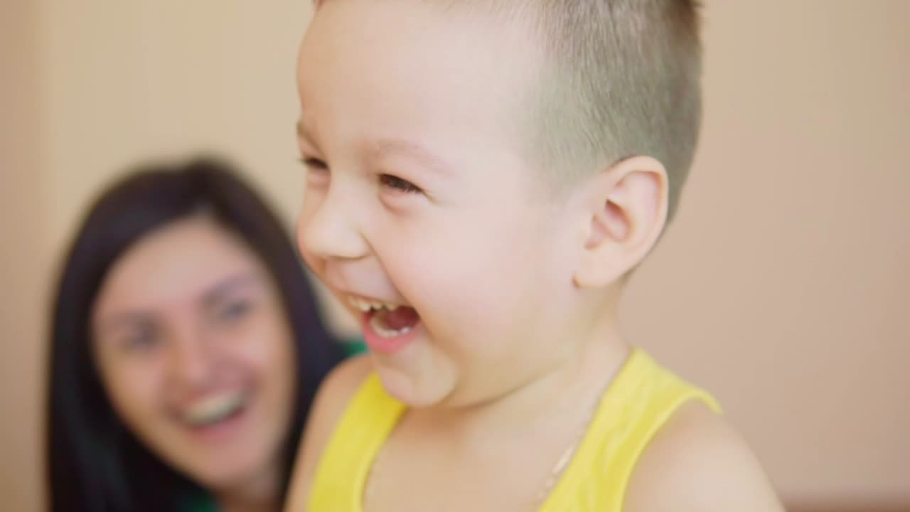 행복한 귀여운 작은 소년은 벽에 그의  ⁇ 은 손자국을 남겨 재미 있습니다. 웃는 행복한 아이의 가까운 시야. 어머니와