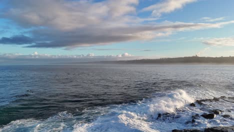 la jolla cove drone backwards reveal of rocks with waves crashing and moody clouds during sunrise