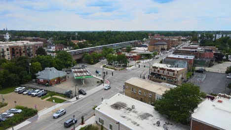 drone shot of lombard, illinois, capturing suburban streets, train tracks, and mixed residential and commercial buildings. crane down left with train cloudy day sw