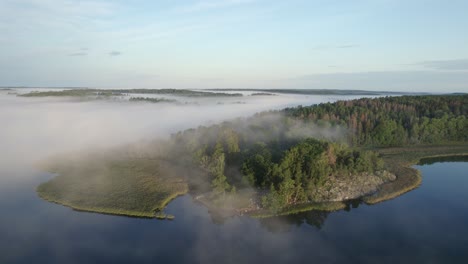 Sol-De-La-Mañana-En-El-Promontorio-Del-Lago-Boscoso-Sueco-Parcialmente-Oscurecido-Por-La-Niebla,-órbita-De-Drones