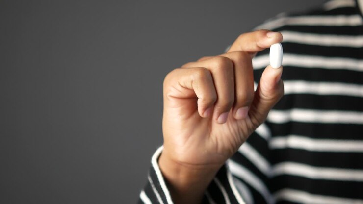 Hand Holding a White Pill
