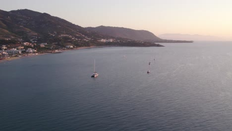 Aerial-view-of-boat-on-calm-sea-with-people-during-sunset,-Cefalu,-Sicily,-Italy