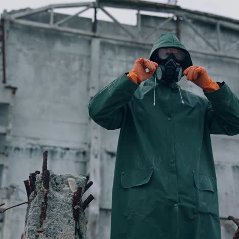 survivor in infected zone. man in protective suit and gas mask putting hood to protect himself from chemical attack in abandoned place