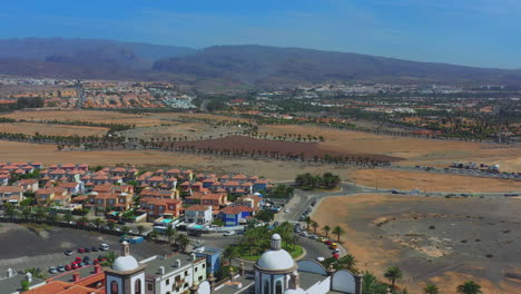 aerial : flying over luxury resorts, discovering wide tropical island with palms and mountains in the distance. aerial footage of luxury island resort with private villas