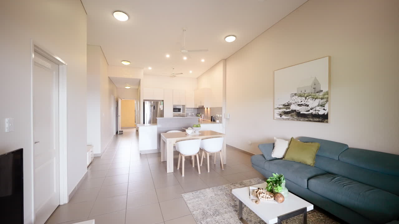 Push In Establish Past Blue Couch and Small Square Table to Rectangular Hallway Floorplan with Vacuum and Staged Decor