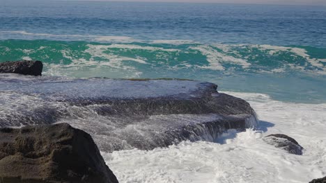 agua de mar que se lava sobre una gran roca a medida que se forma una nueva ola