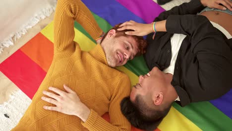 happy gay couple lying on rainbow pride flag