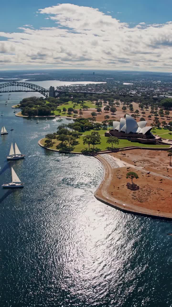 Aerial video captures a scenic view of a coastal city with iconic architecture and sailboats