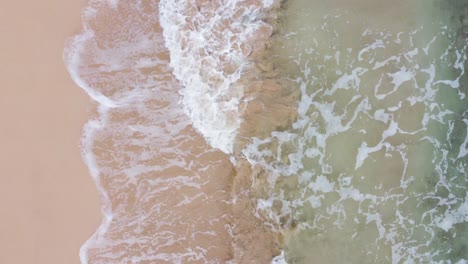 Fast-moving-Aerial-top-view-over-clear,-Turquoise-ocean-water-foaming-at-the-shore,-washing-the-golden-sand-of-the-beach,-Idyllic-summer-vacation-on-Hawaii-island