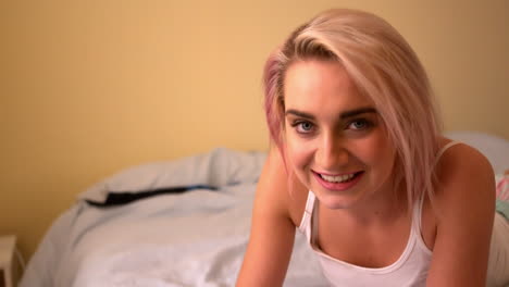 joven rubia muy acostada en la cama usando la tableta