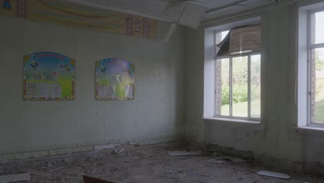 abandoned classroom with damaged walls, scattered debris, and evidence of structural collapse