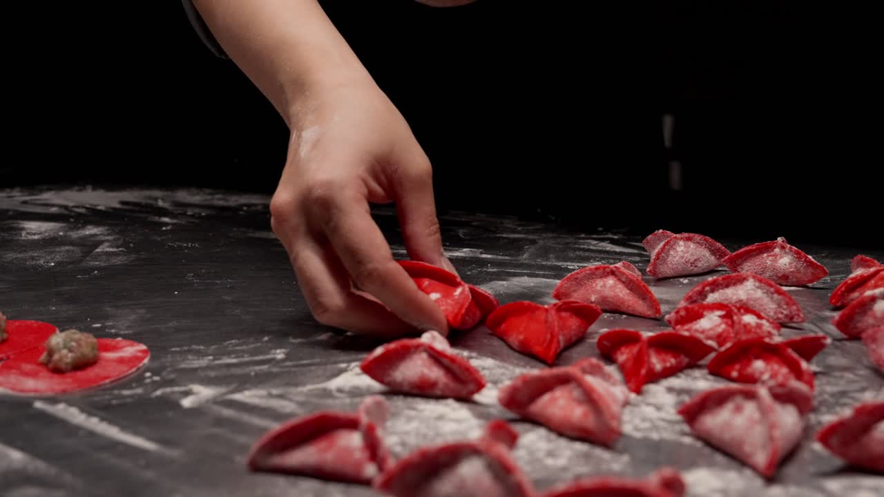 Chef's Hand Placing Red Dumpling on Floured Surface