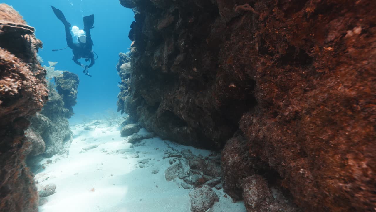 Scuba Diver Swimming Through a Narrow Coral Passage — Dramatic Underwater Exploration in a Scenic Tropical Reef Environment — Captured in Stunning 4K 60 FPS for Premium Stock Footage