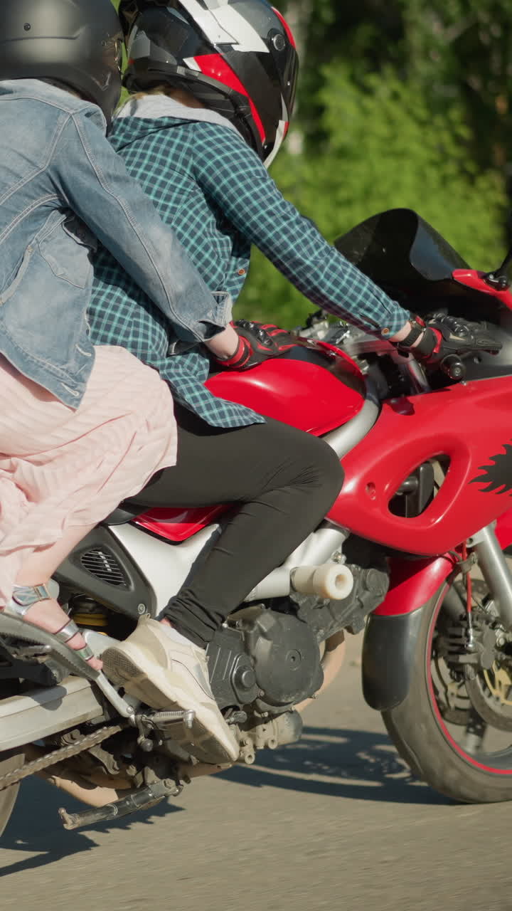 두 명의 여성이 도시 도로를 따라 전력 자전거를 타고, 승객은 나무와 건물을 지나갈 때 라이더를 붙잡고 있습니다.