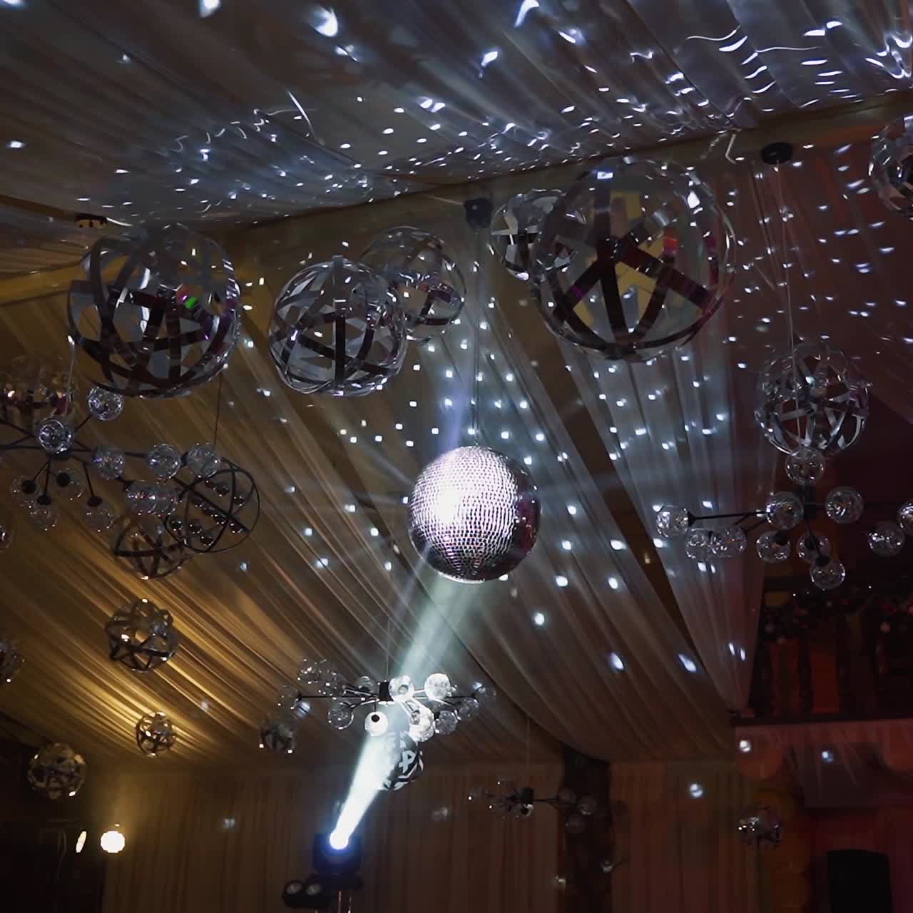 Shining sphere of a night club. Many balls hanging on a shining ceiling at a party. Disco ball spinning and reflecting silver lights.