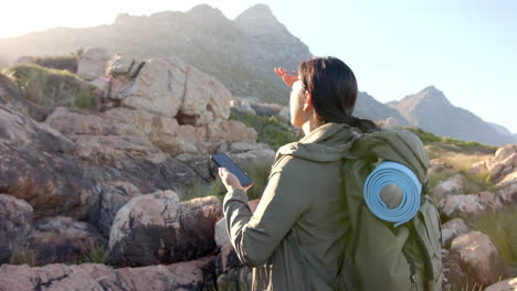 hiking in mountains, woman with backpack holding smartphone and looking ahead