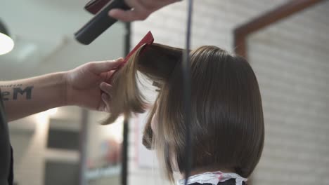 Primer-Plano-De-Una-Mujer-Alisándose-El-Cabello-En-Una-Peluquería.-Filmado-En-Cámara-Lenta