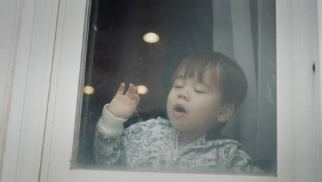 a little boy looks out the window, reacts emotionally and cheerfully to what he saw. multi-ethnic child of two years