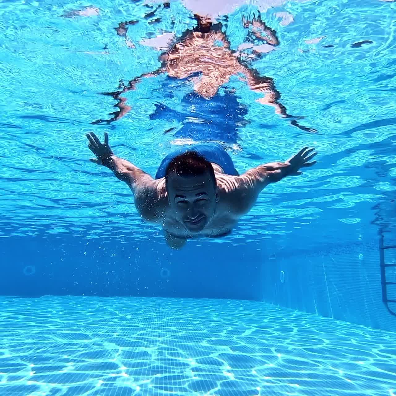 Man sitting underwater in yoga pose. Underwater view inside the swimming pool of a healthy man doing exercise. Underwater sport.