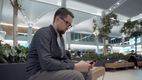 hombre usando teléfono inteligente en la terminal moderna del aeropuerto