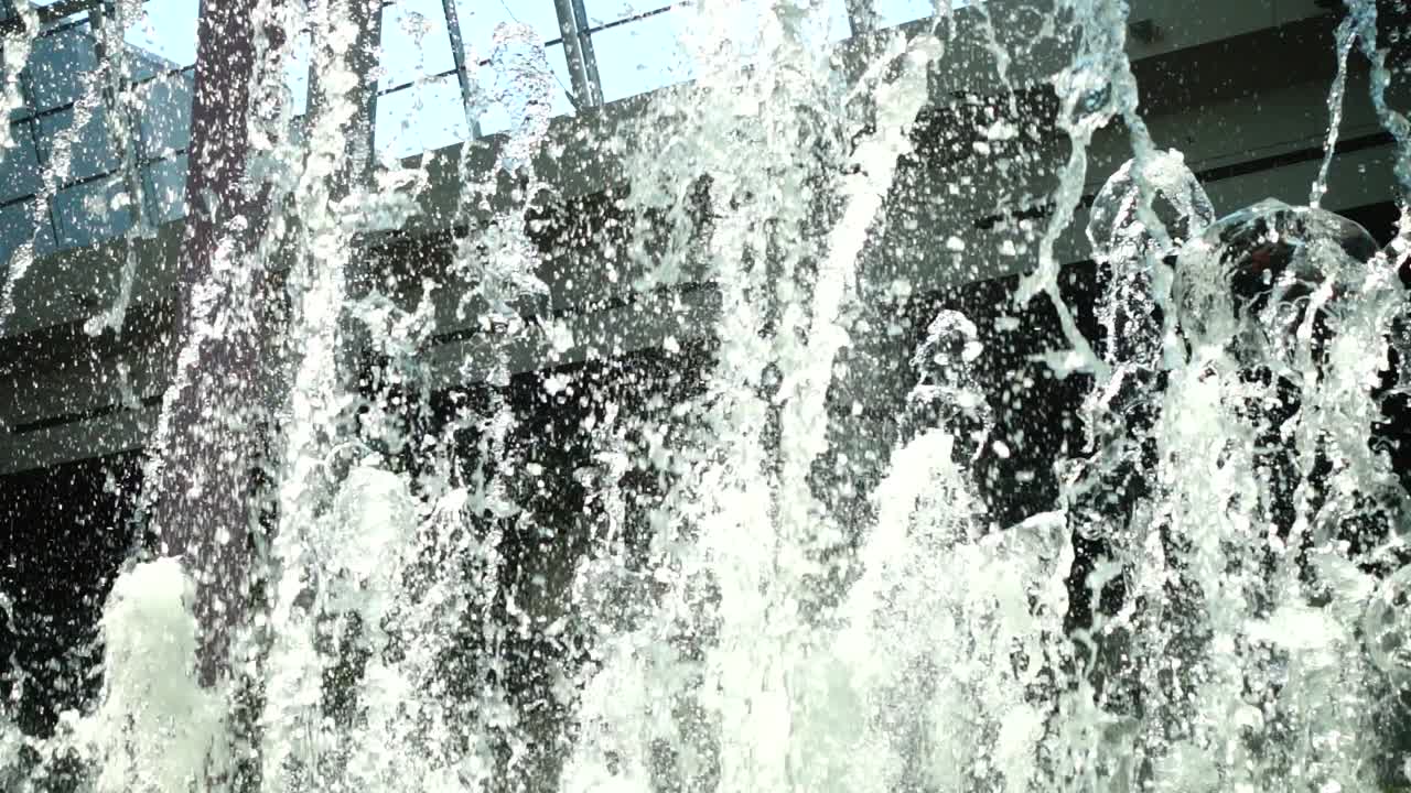 Fonteinstralen in het winkelcentrum. Vertraagde beweging.