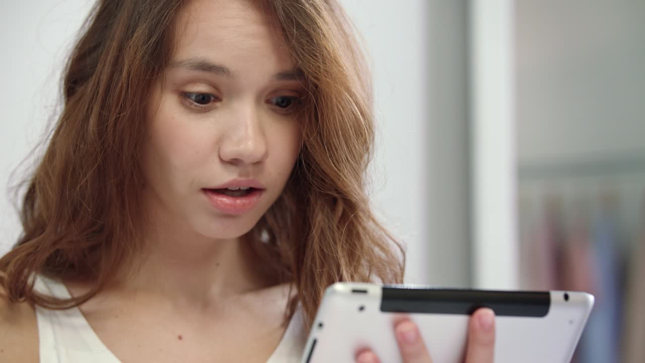 태블릿 컴퓨터를 보는 놀라운 여성 얼굴. 충격적인 여성 감정