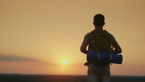 Ein-Junger-Männlicher-Tourist-Mit-Rucksack-Schaut-Auf-Den-Horizont,-Wo-Die-Sonne-Untergeht-4k-Video-Zurück