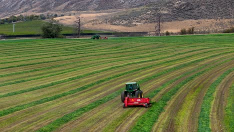 precisión agrícola: tedding, rastrillo y un tractor verde en acción en los campos circulares de la columbia británica