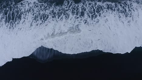 powerful atlantic waves rolling in on black sand beach in iceland - aerial ascending straight down