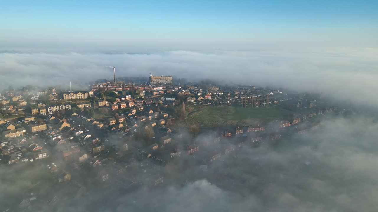 Letecký pohled z dronu na anglickou městskou krajinu za východu slunce, zářící slunce na zatažené mlhavé obloze, malebná scenérie