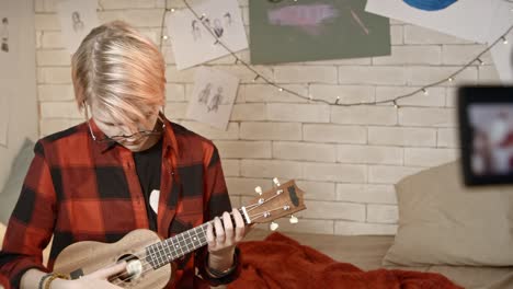 teenage girl filming herself playing ukulele