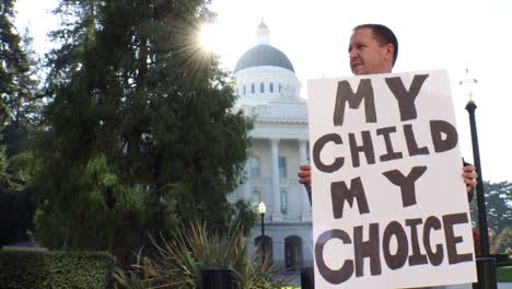 male political protester with my child my choice sign