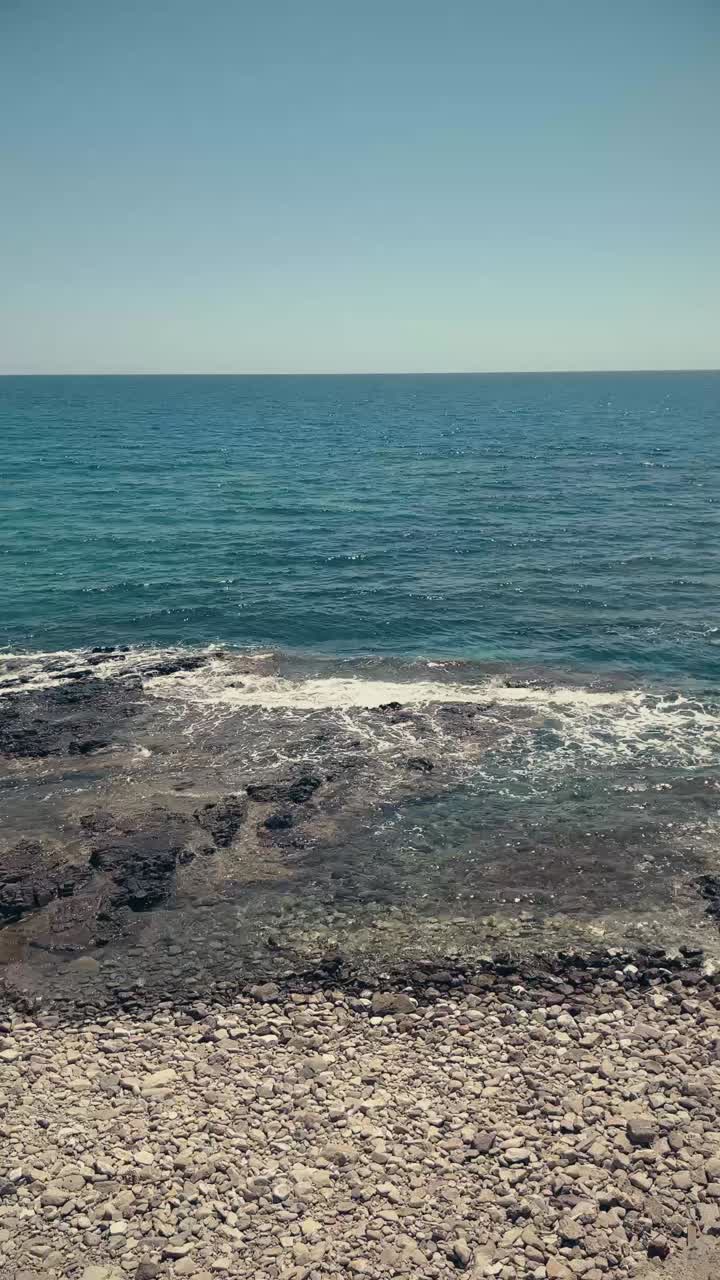 Acqua cristallina blu dell'oceano e onde su una costa rocciosa