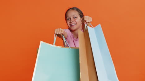 child girl kid showing shopping bags, advertising discounts, smiling amazed with low prices holidays