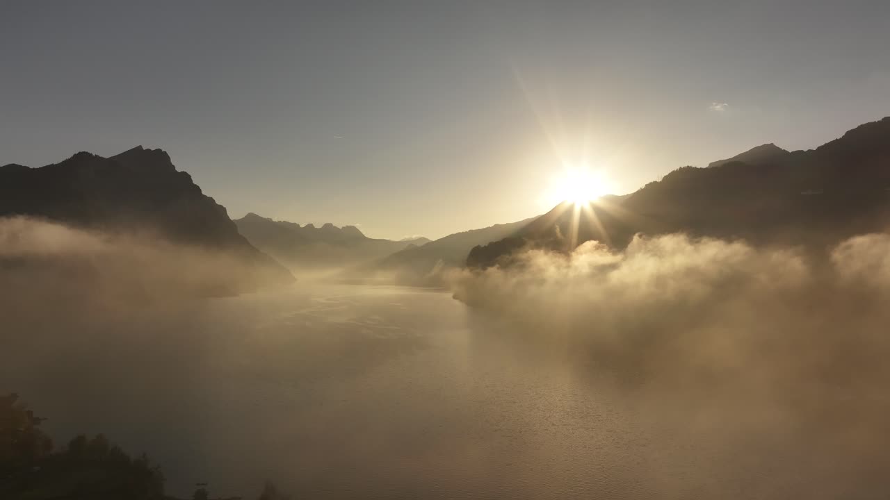 Golden sunrise over Walensee, Switzerland, with mist drifting across the lake