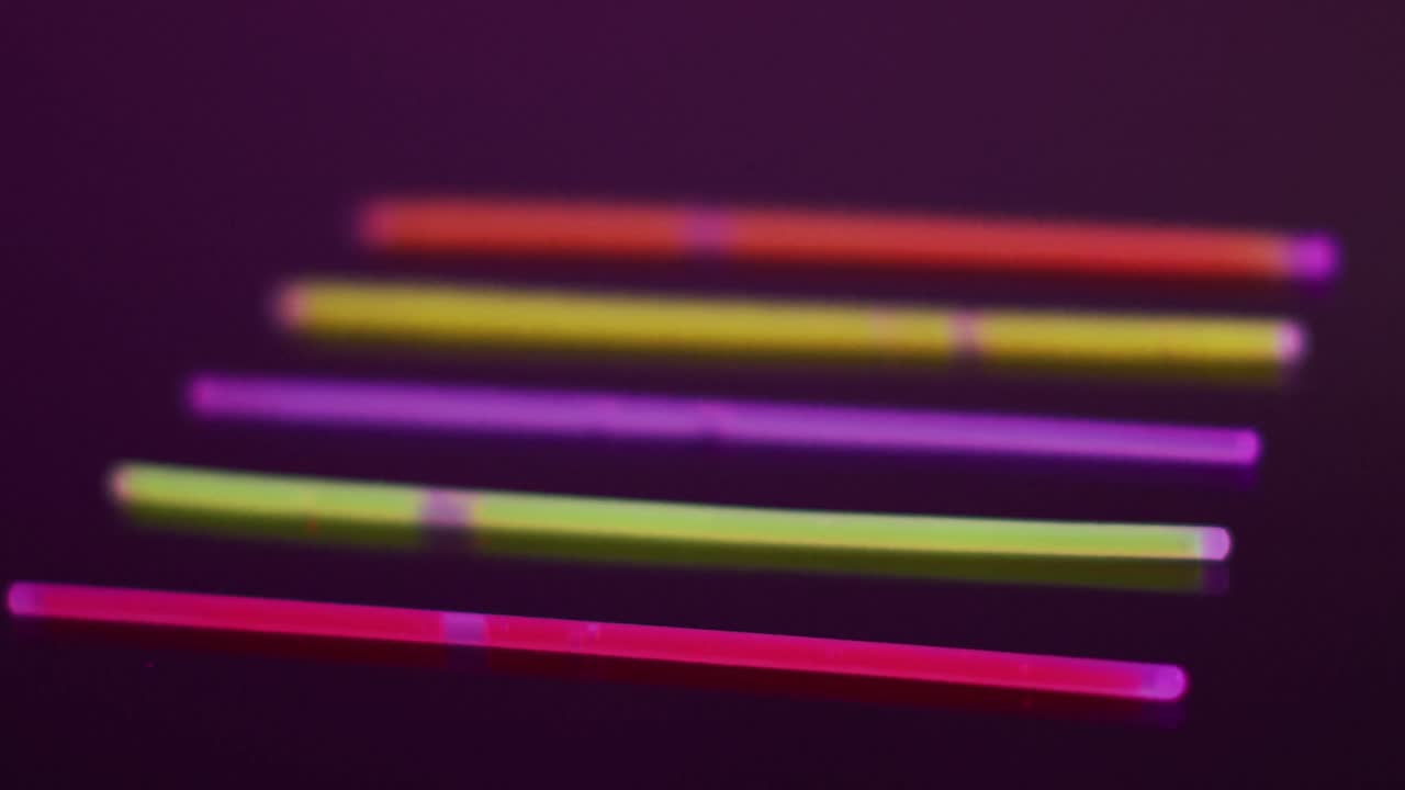Animation of five colorful neon glow sticks over black background