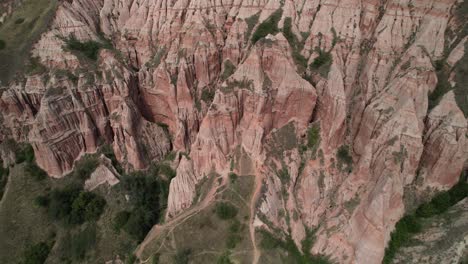 cinematic aerial view down on the rapa rosie canyon in romania. orbiting around red cliffs.